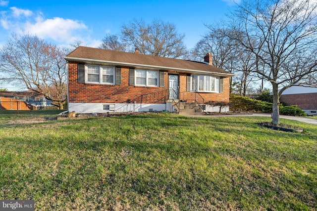 view of front of property with a chimney, fence, a front lawn, and brick siding
