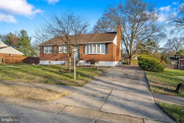 view of front of home with fence, a chimney, concrete driveway, a front yard, and brick siding