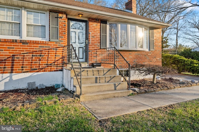 property entrance featuring brick siding and a chimney