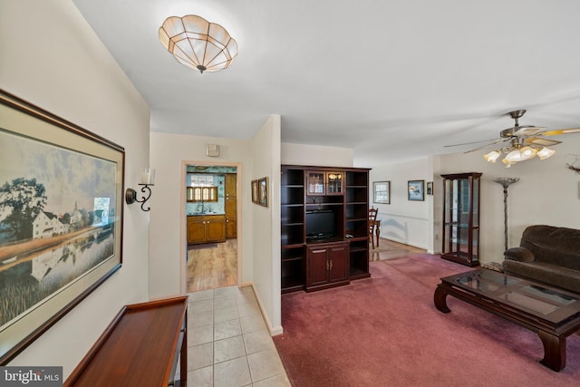 living room with baseboards, ceiling fan, carpet floors, and tile patterned flooring
