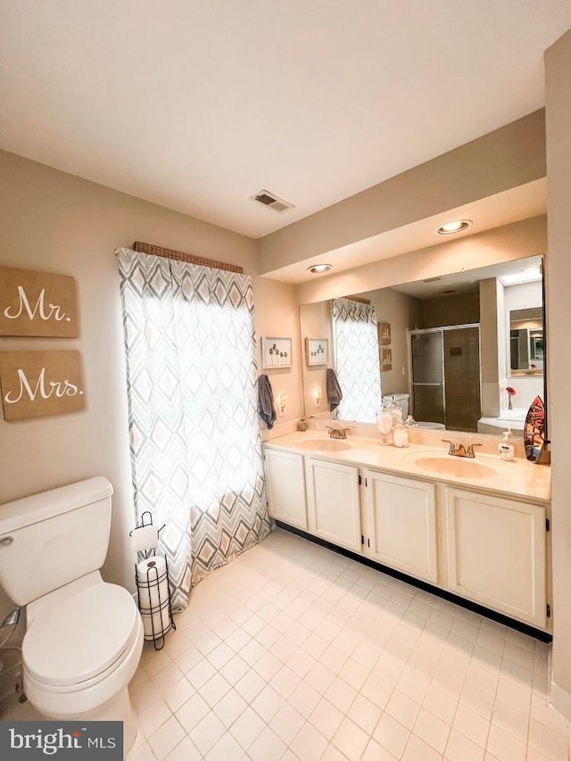full bathroom with a shower stall, toilet, a sink, and double vanity