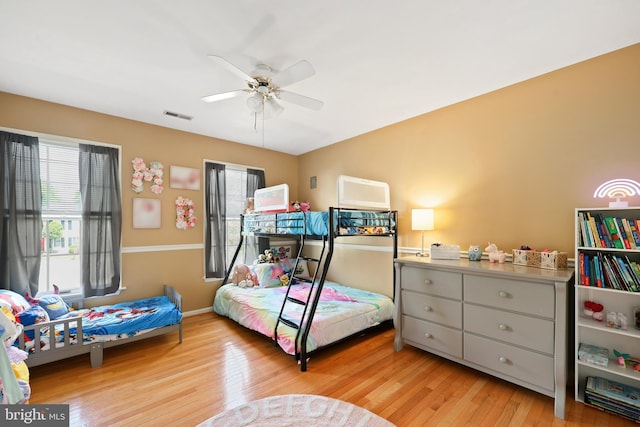 bedroom with a ceiling fan, wood finished floors, and visible vents