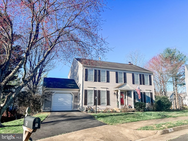 colonial-style house featuring a garage, driveway, and a front yard