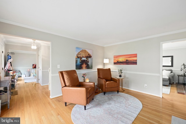 sitting room featuring baseboards, crown molding, and light wood-style floors