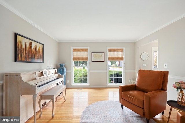 living area with baseboards, ornamental molding, wood finished floors, and visible vents