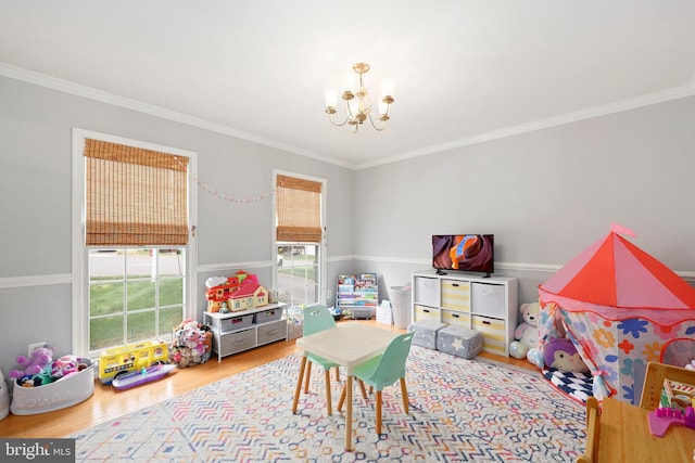 recreation room with wood finished floors, an inviting chandelier, and crown molding