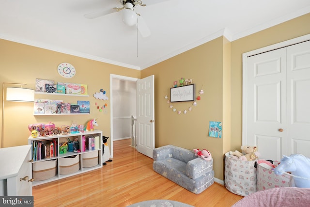 playroom with ceiling fan, baseboards, ornamental molding, and light wood-style floors
