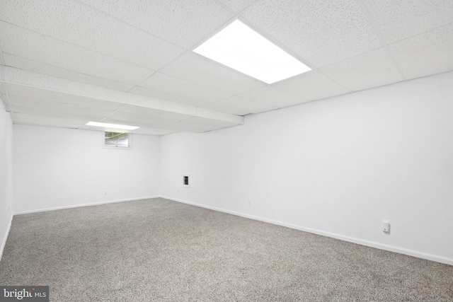 basement with carpet floors, a drop ceiling, and baseboards
