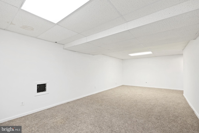 finished below grade area featuring carpet flooring, a drop ceiling, and baseboards