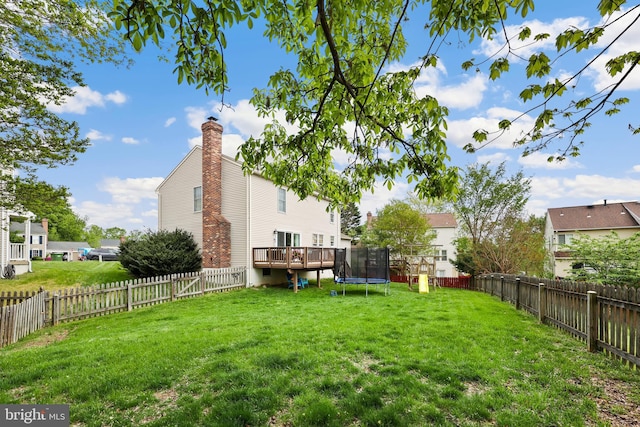 view of yard with a wooden deck, a trampoline, and a fenced backyard