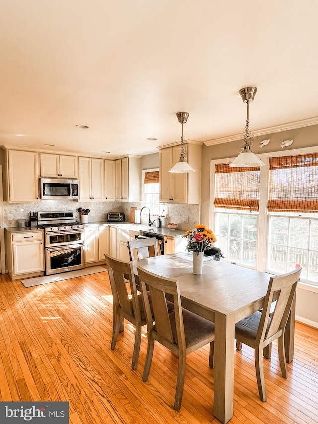 dining room with ornamental molding and light wood-style floors