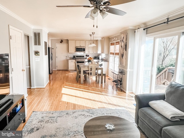 living area with crown molding, ceiling fan, light wood finished floors, baseboards, and visible vents