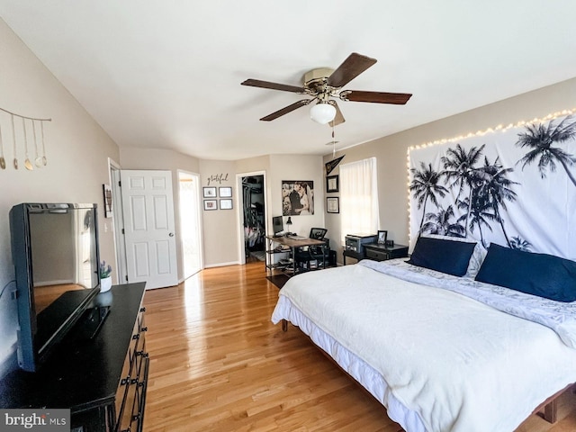 bedroom with light wood finished floors, a spacious closet, a closet, and ceiling fan