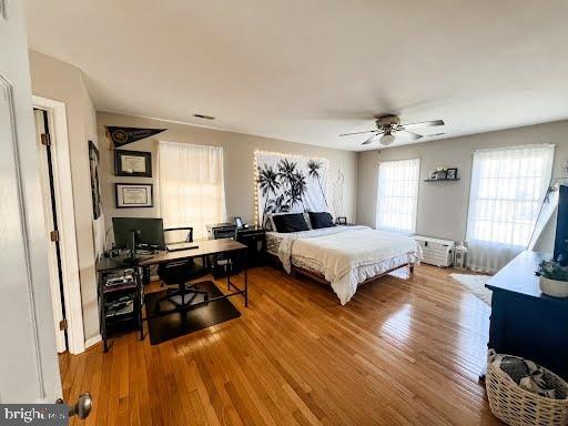 bedroom featuring a ceiling fan, wood finished floors, and visible vents