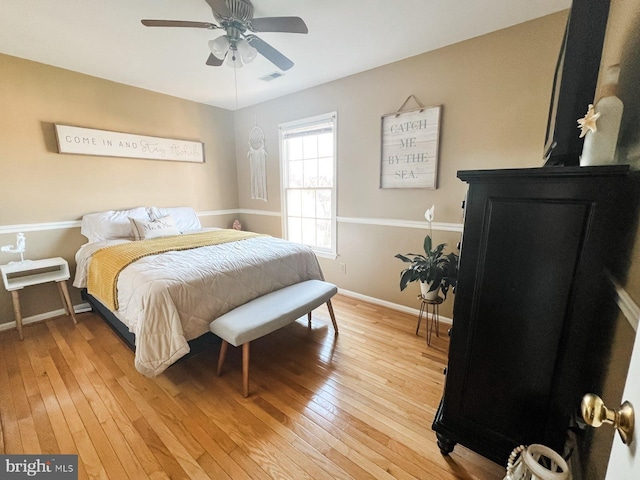 bedroom with baseboards, a ceiling fan, visible vents, and light wood-style flooring
