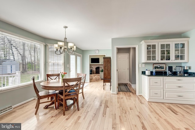 5855 Springmount Ct, Eldersburg, MD 21784 - dining space featuring light wood-style floors, a fireplace, baseboards, a notable chandelier, and visible vents