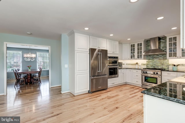 5855 Springmount Ct, Eldersburg, MD 21784 - kitchen with wall chimney range hood, premium appliances, decorative backsplash, an inviting chandelier, and white cabinetry