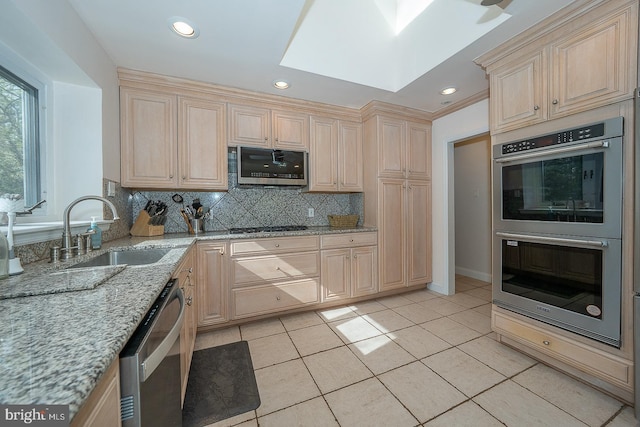 kitchen featuring stainless steel appliances, tasteful backsplash, light brown cabinetry, and a sink