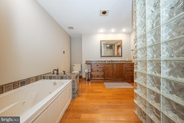 full bathroom with wood finished floors, a tub with jets, visible vents, vanity, and recessed lighting