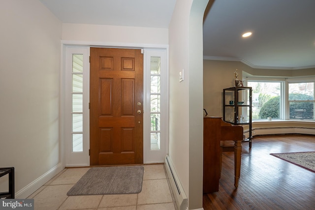 foyer entrance featuring wood finished floors, baseboards, a baseboard heating unit, and arched walkways