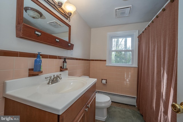 bathroom with tile walls, toilet, a baseboard heating unit, vanity, and visible vents