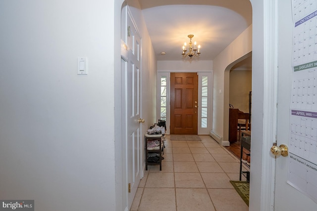 entryway with baseboard heating, baseboards, light tile patterned floors, a chandelier, and arched walkways