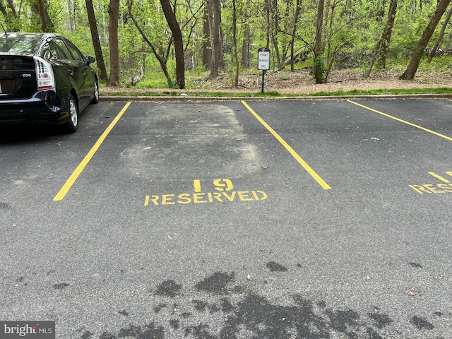 uncovered parking lot featuring a view of trees