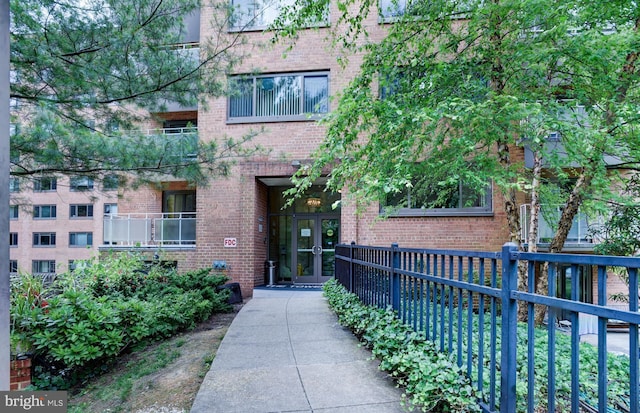entrance to property with brick siding, french doors, and fence