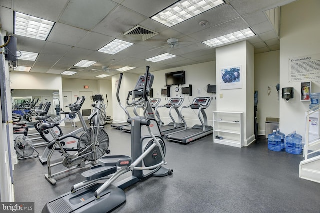 gym with ceiling fan, baseboards, visible vents, and a paneled ceiling