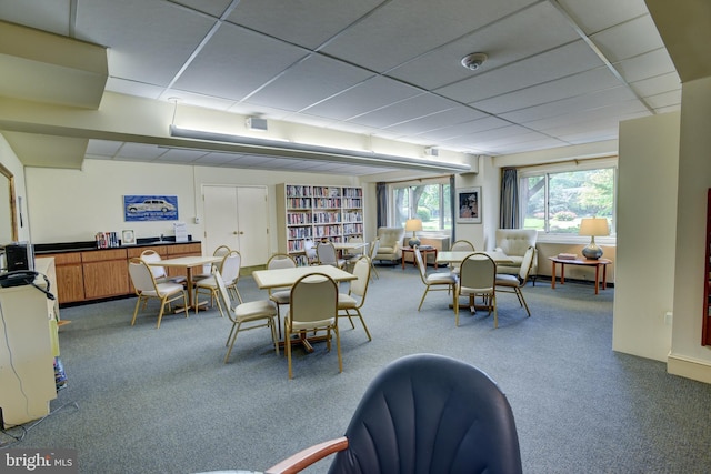 carpeted dining area featuring a drop ceiling