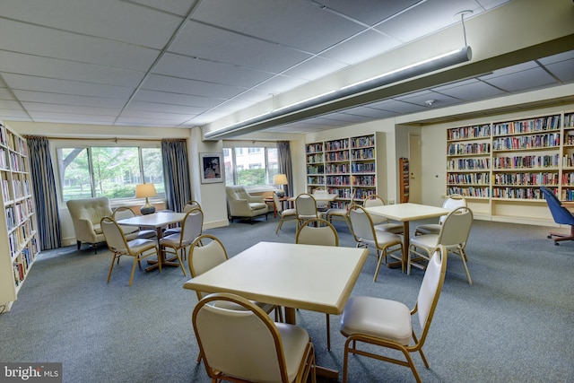 carpeted dining area featuring a paneled ceiling