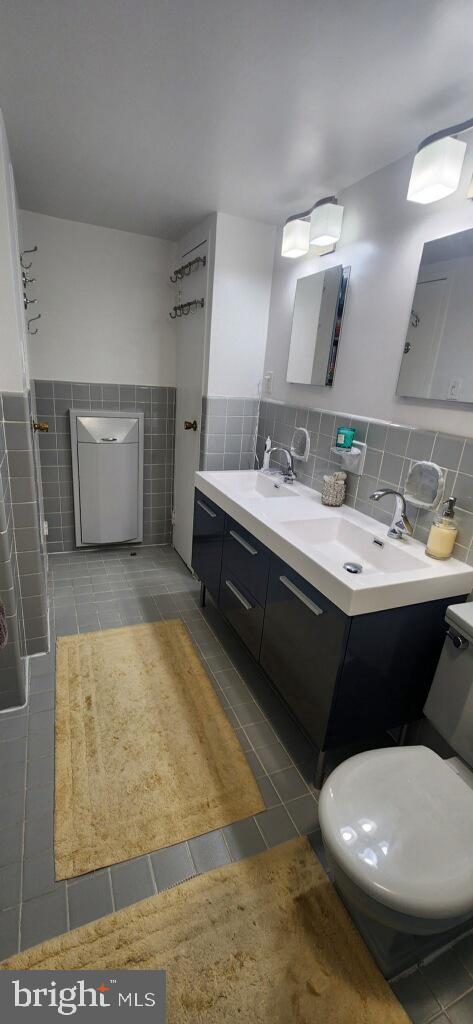 bathroom with double vanity, tile walls, tile patterned floors, and a sink