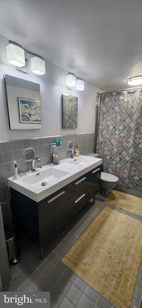 bathroom featuring curtained shower, tile walls, tile patterned floors, and toilet