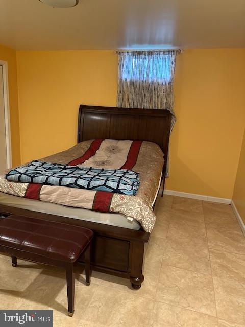 bedroom with light tile patterned floors and baseboards
