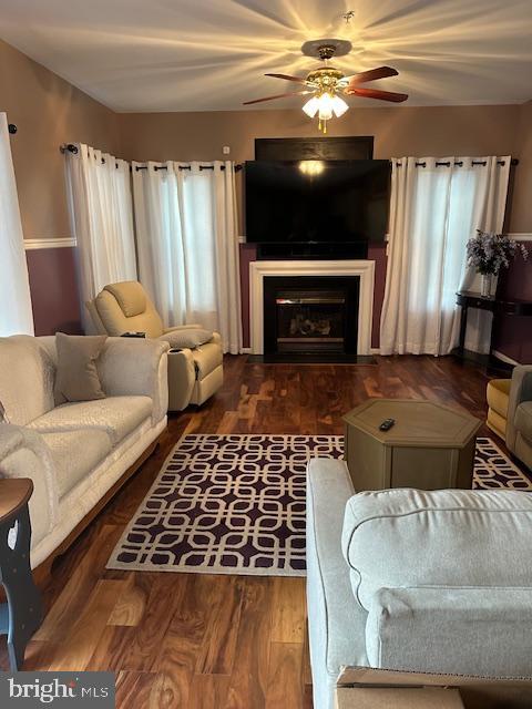 living room featuring a ceiling fan, plenty of natural light, wood finished floors, and a fireplace