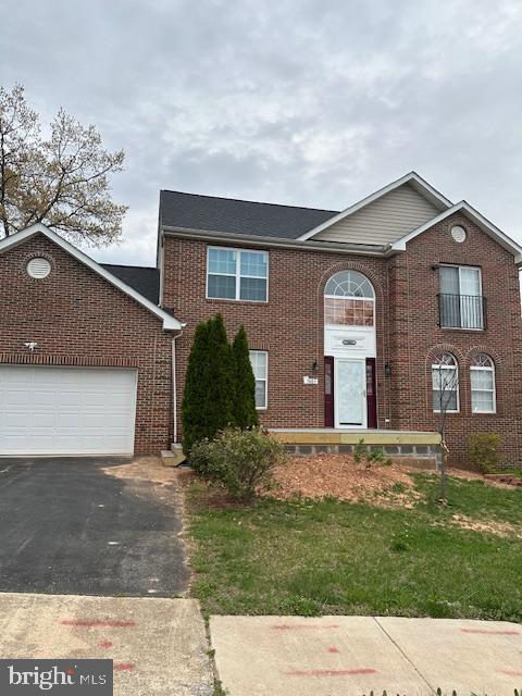 view of front facade featuring aphalt driveway, brick siding, an attached garage, and a front yard