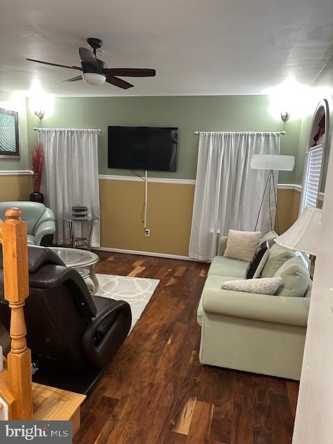 living room with baseboards, wood finished floors, and ceiling fan