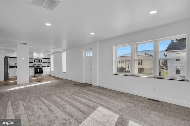 unfurnished living room with light carpet, baseboards, visible vents, and recessed lighting