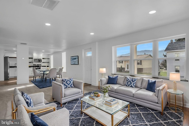 living room with baseboards, wood finished floors, visible vents, and recessed lighting