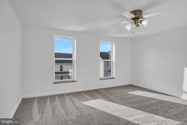 carpeted empty room featuring ceiling fan and baseboards