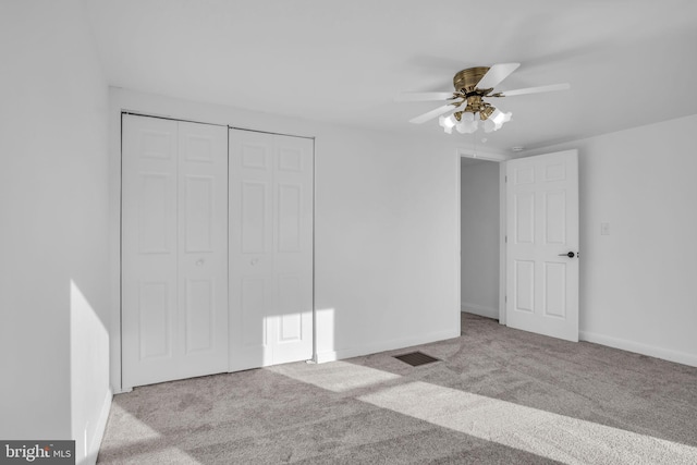 unfurnished bedroom featuring baseboards, visible vents, carpet, a closet, and ceiling fan