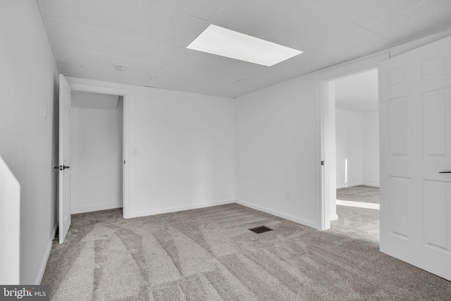 spare room with carpet, visible vents, a drop ceiling, and baseboards