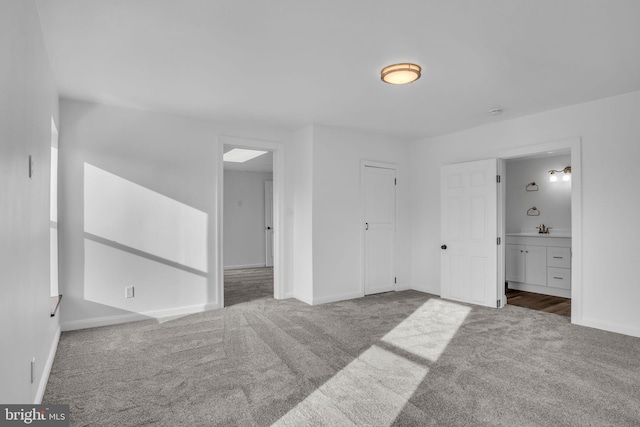 unfurnished bedroom featuring ensuite bath, baseboards, carpet floors, and a sink