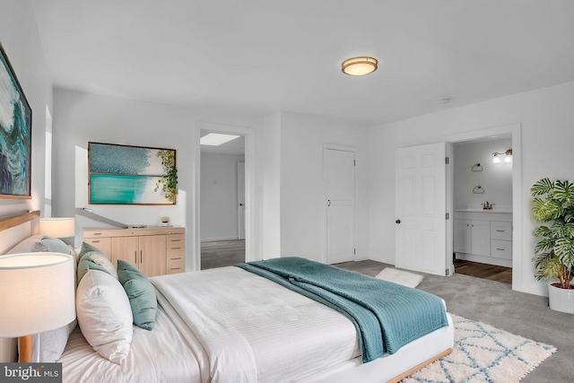 bedroom featuring ensuite bath, a sink, and light colored carpet