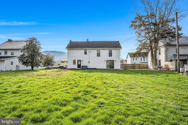 rear view of house with a yard, fence, and a mountain view