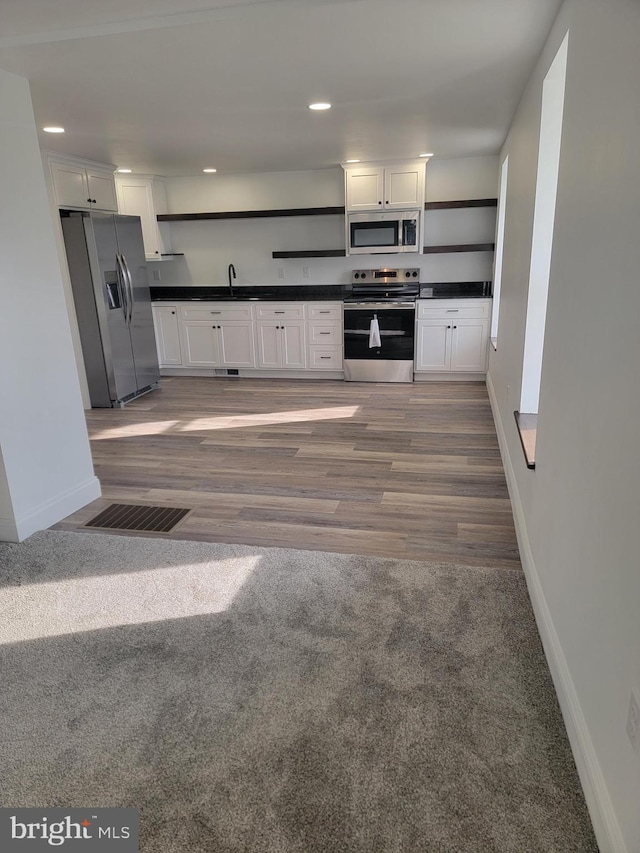 kitchen featuring dark countertops, open shelves, white cabinetry, and stainless steel appliances