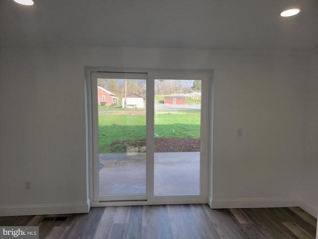 doorway to outside featuring visible vents, baseboards, and wood finished floors
