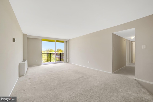 unfurnished room featuring floor to ceiling windows, baseboards, light colored carpet, and radiator heating unit