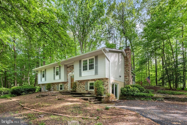 split foyer home with a chimney and driveway