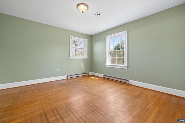 unfurnished room with baseboards, visible vents, and a baseboard heating unit